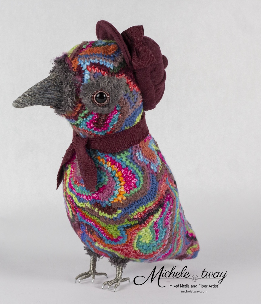 Maya is a mixed media fiber art sculpture featuring a crochet body and an embroidered beak.