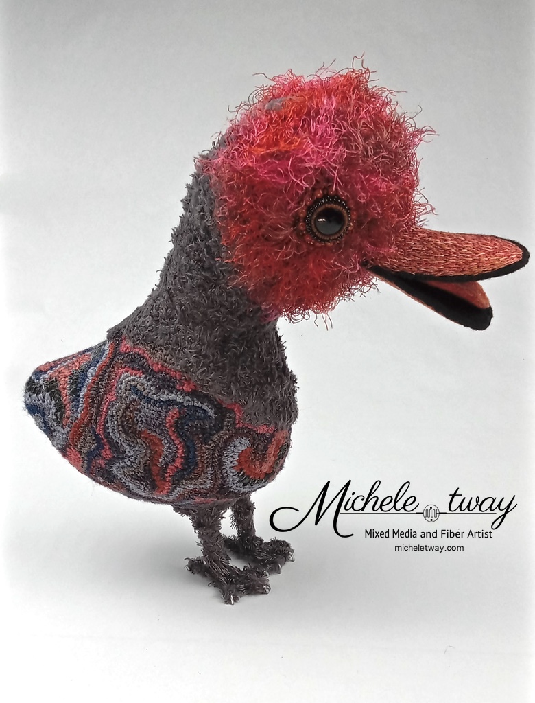 Maya is a mixed media fiber art sculpture featuring a crochet body and an embroidered beak.