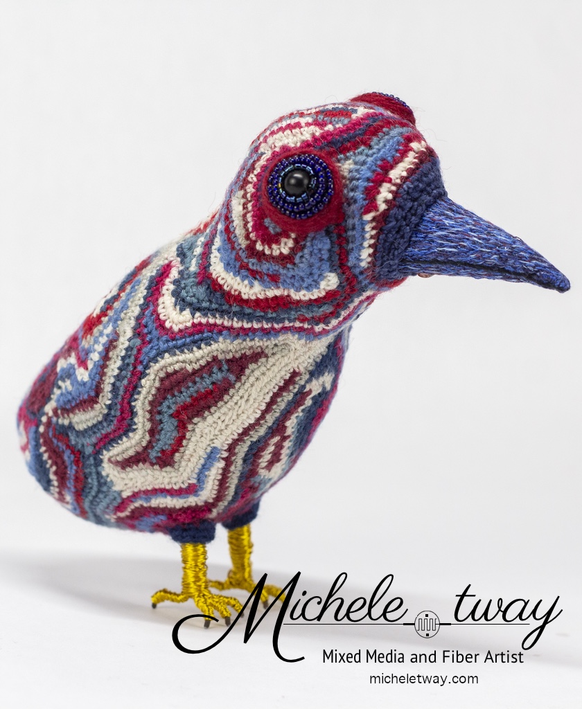 Maya is a mixed media fiber art sculpture featuring a crochet body and an embroidered beak.