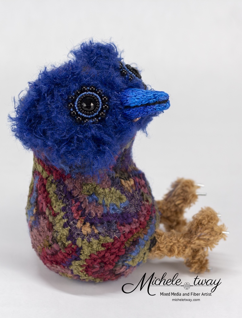 Maya is a mixed media fiber art sculpture featuring a crochet body and an embroidered beak.